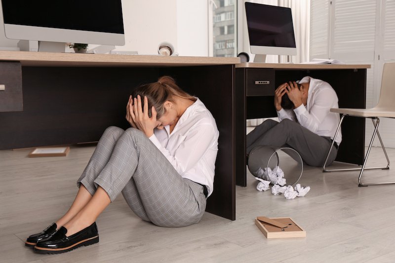 Office workers taking cover under desks during earthquake shaking, illustrating why P-wave and S-wave detection matters